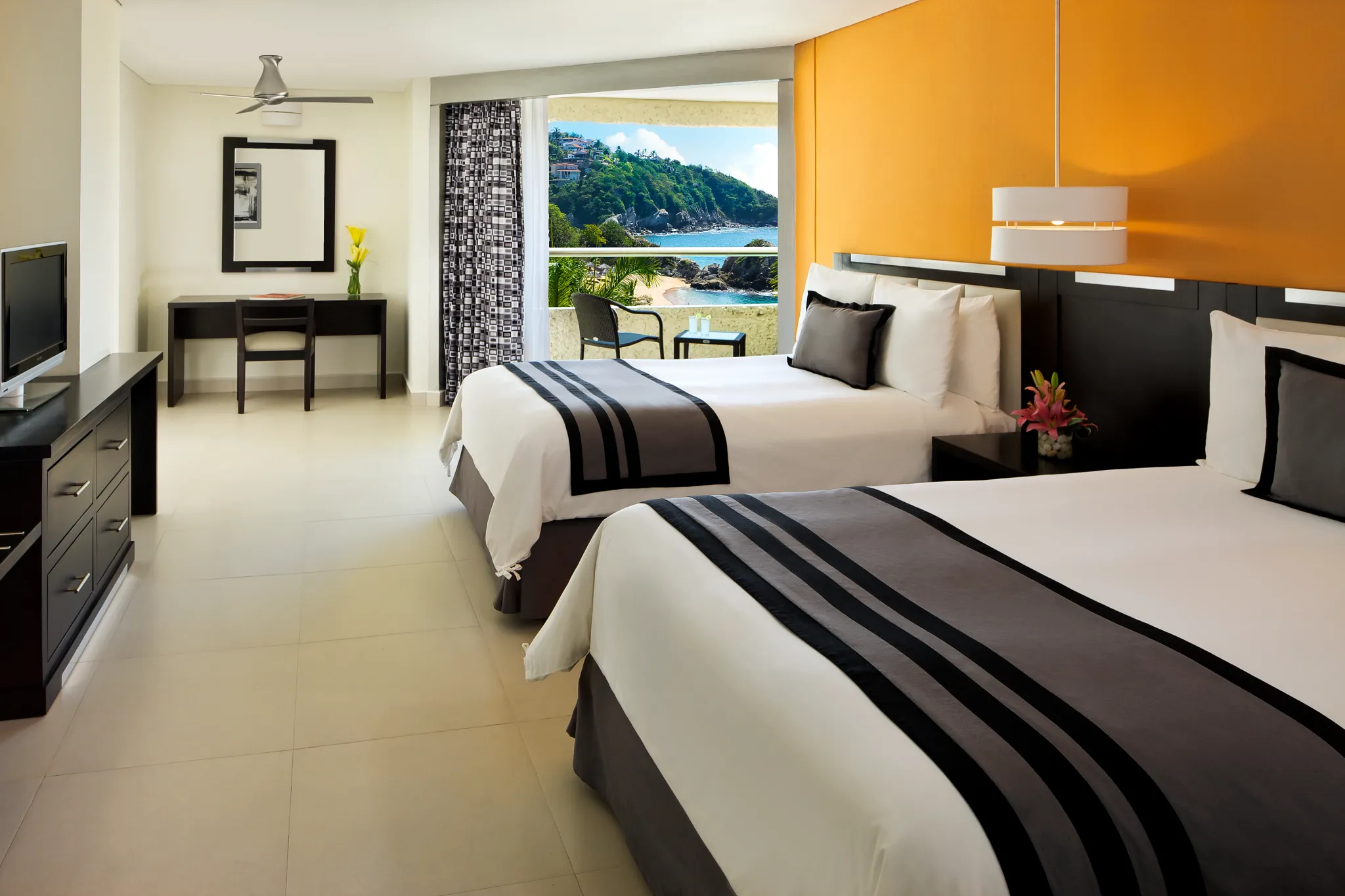 Deluxe Partial Ocean View room with two double beds at Dreams Huatulco Resort & Spa overlooking the coastline.