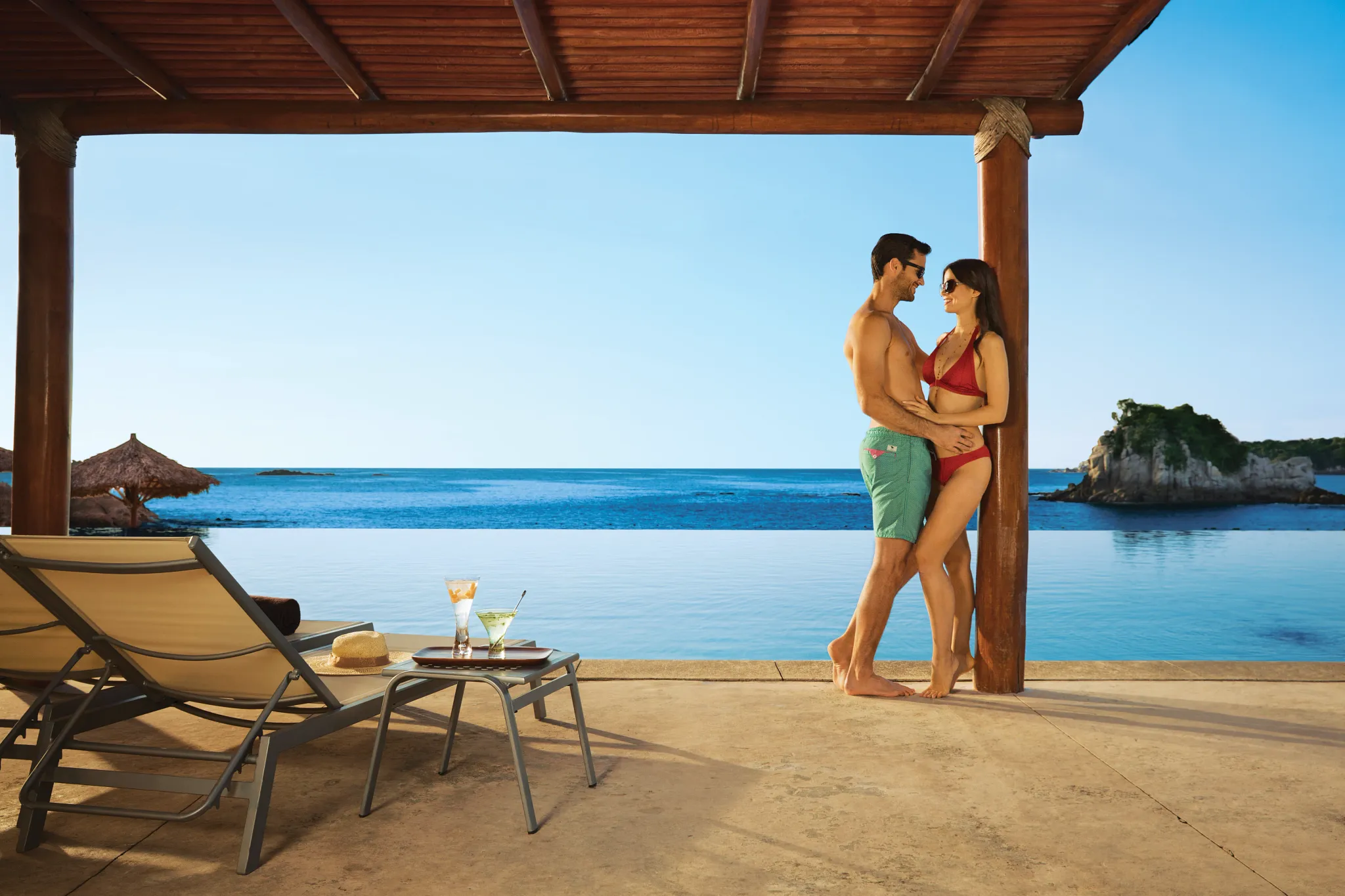 Couple sharing a romantic moment under a poolside pergola at Dreams Huatulco Resort & Spa.