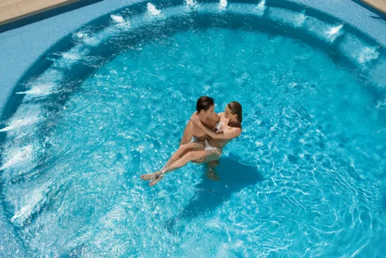 Couple relaxing together in an outdoor whirlpool at Dreams Huatulco Resort & Spa.
